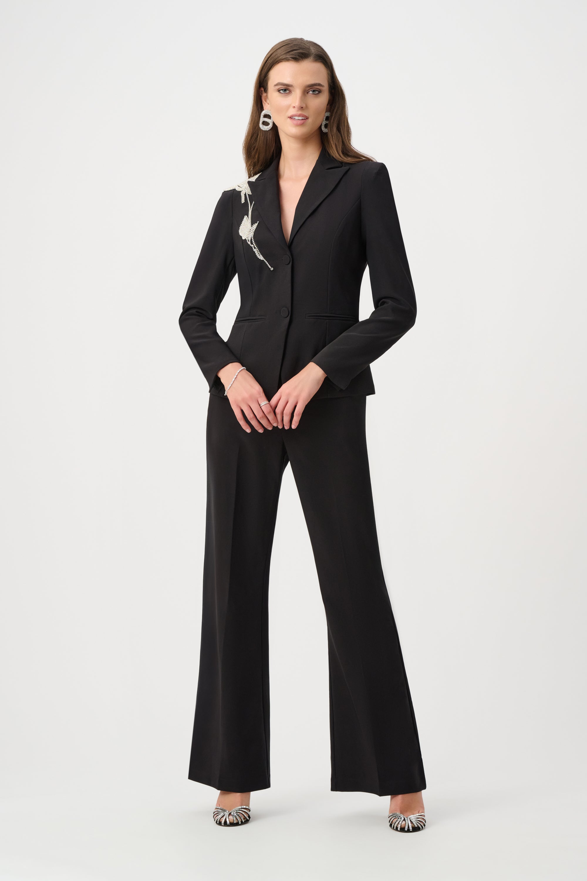 women wearing black pants and black blazer with rhinestones on shoulder on plain white background