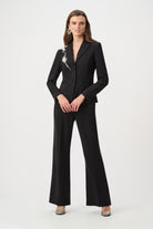 women wearing black pants and black blazer with rhinestones on shoulder on plain white background