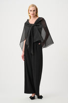 Woman wearing a black outfit with a large black scarf on a white background