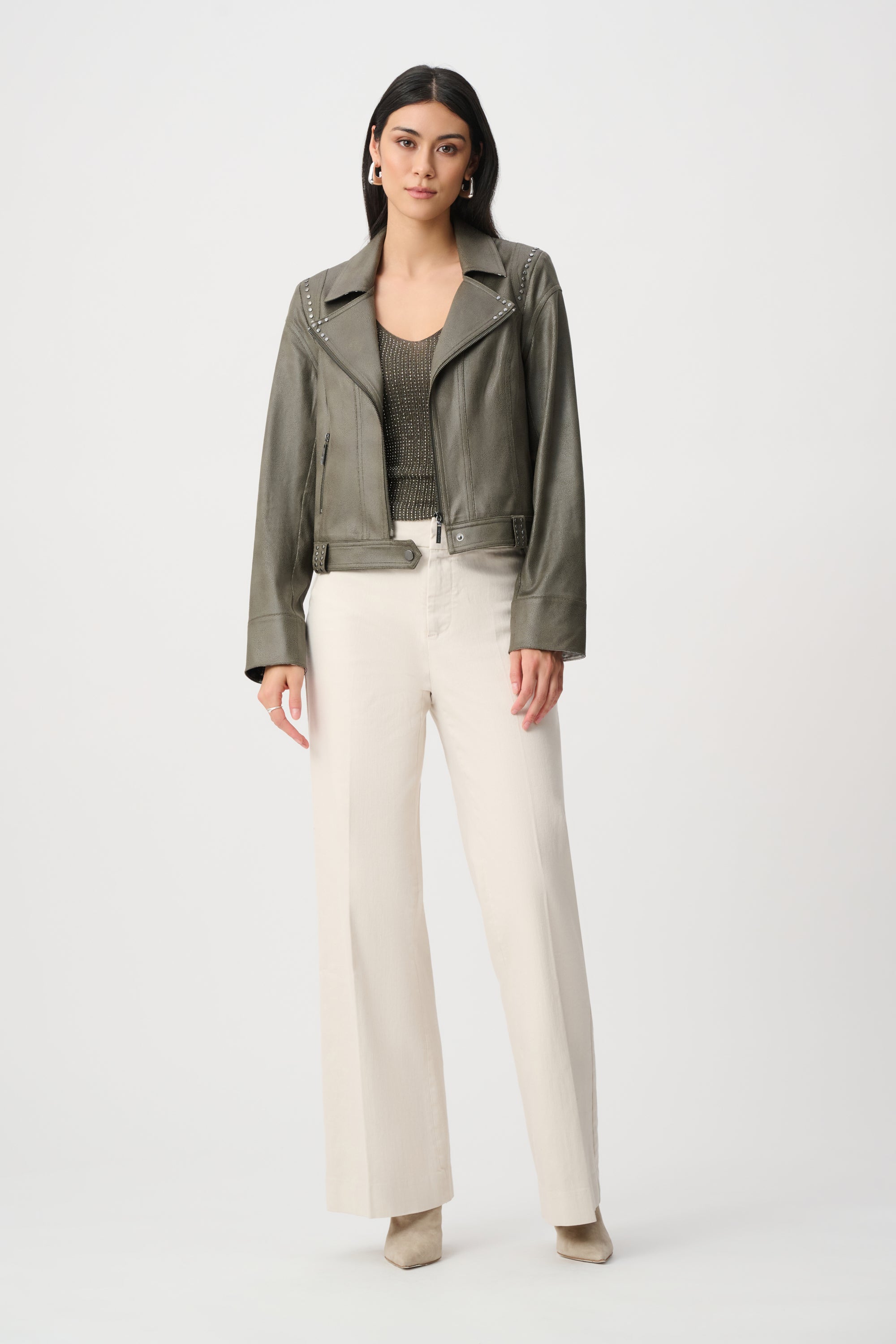 Woman wearing a green jacket and white pants on a white background