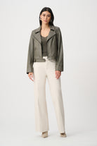 Woman wearing a green jacket and white pants on a white background