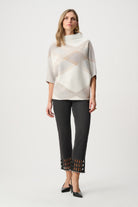women wearing a white knit top with a pattern and black pants on a white background