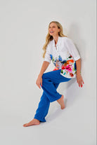 Woman wearing a colorful floral blouse and blue pants on a white background