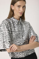 Woman wearing a patterned blouse against a plain background