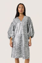 Woman wearing a patterned dress on a plain background