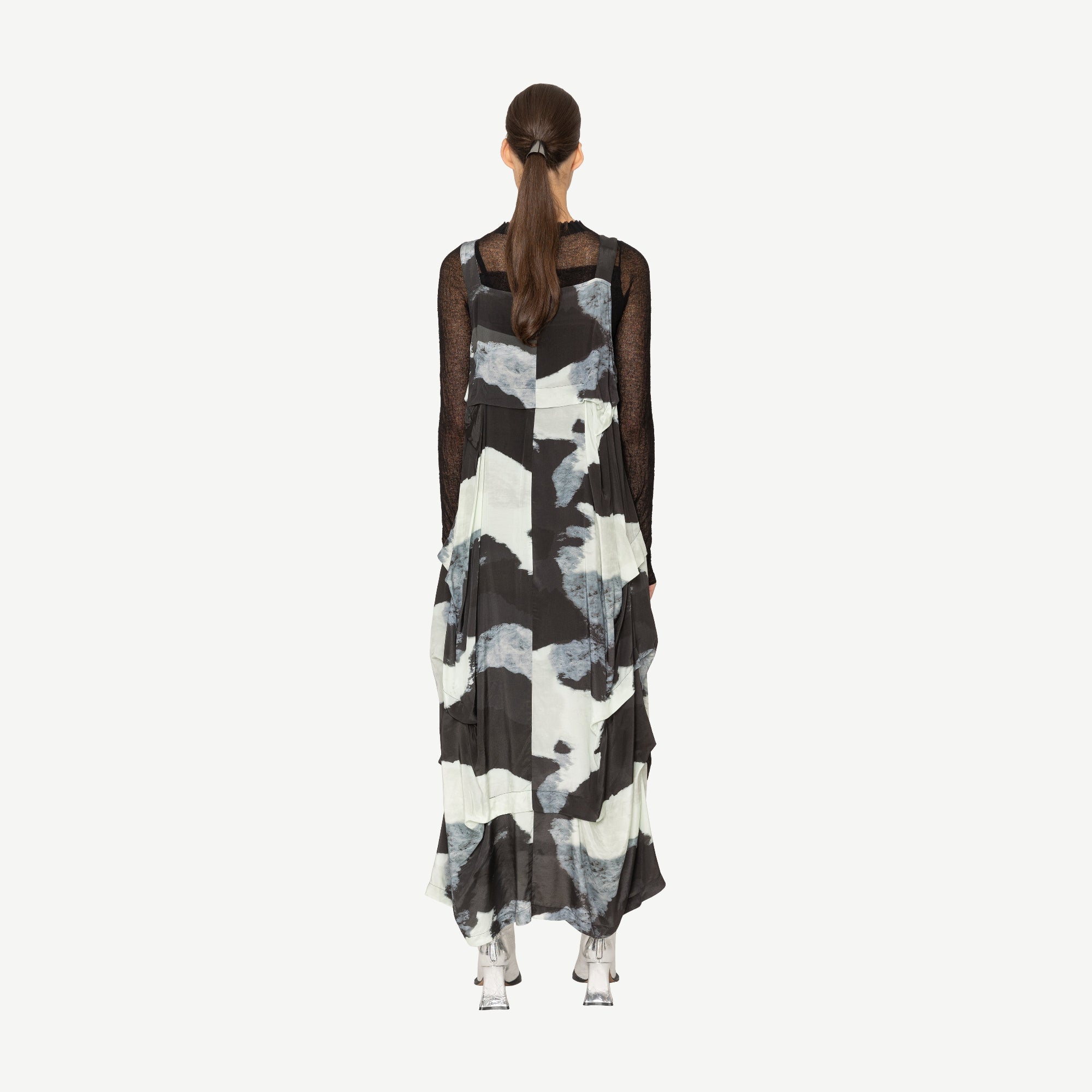 Woman wearing a black and white patterned dress on a white background back angle