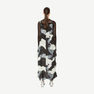 Woman wearing a black and white patterned dress on a white background back angle