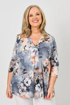 Woman wearing a floral blouse against a plain background