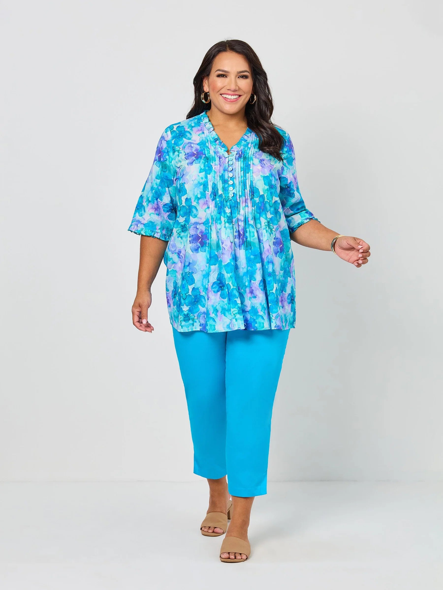 Woman wearing a colorful blouse and blue pants on a white background