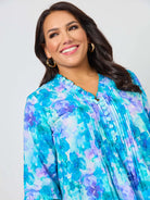 Woman wearing a blue and purple floral blouse against a plain background