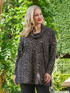 Woman wearing a zebra print sweater in an outdoor setting with greenery.