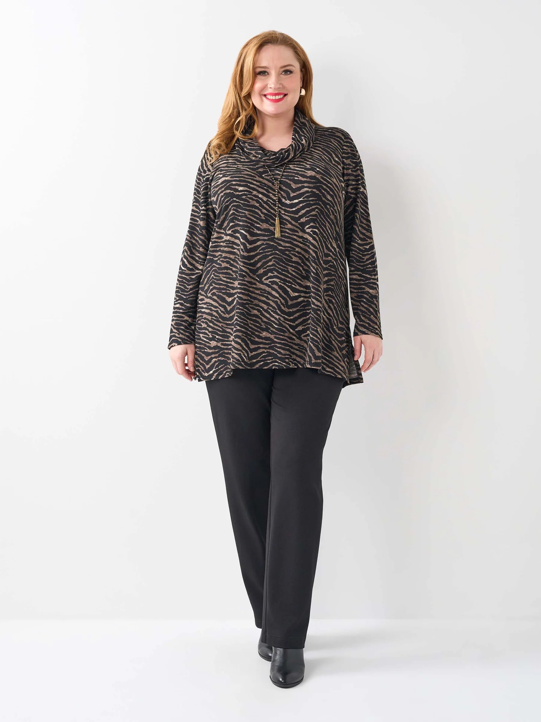 Woman wearing a patterned top and black pants on a white background