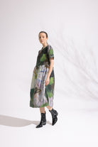 Woman wearing a patterned dress with black boots on a white background