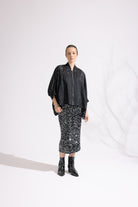 Person wearing a black patterned outfit on a white background