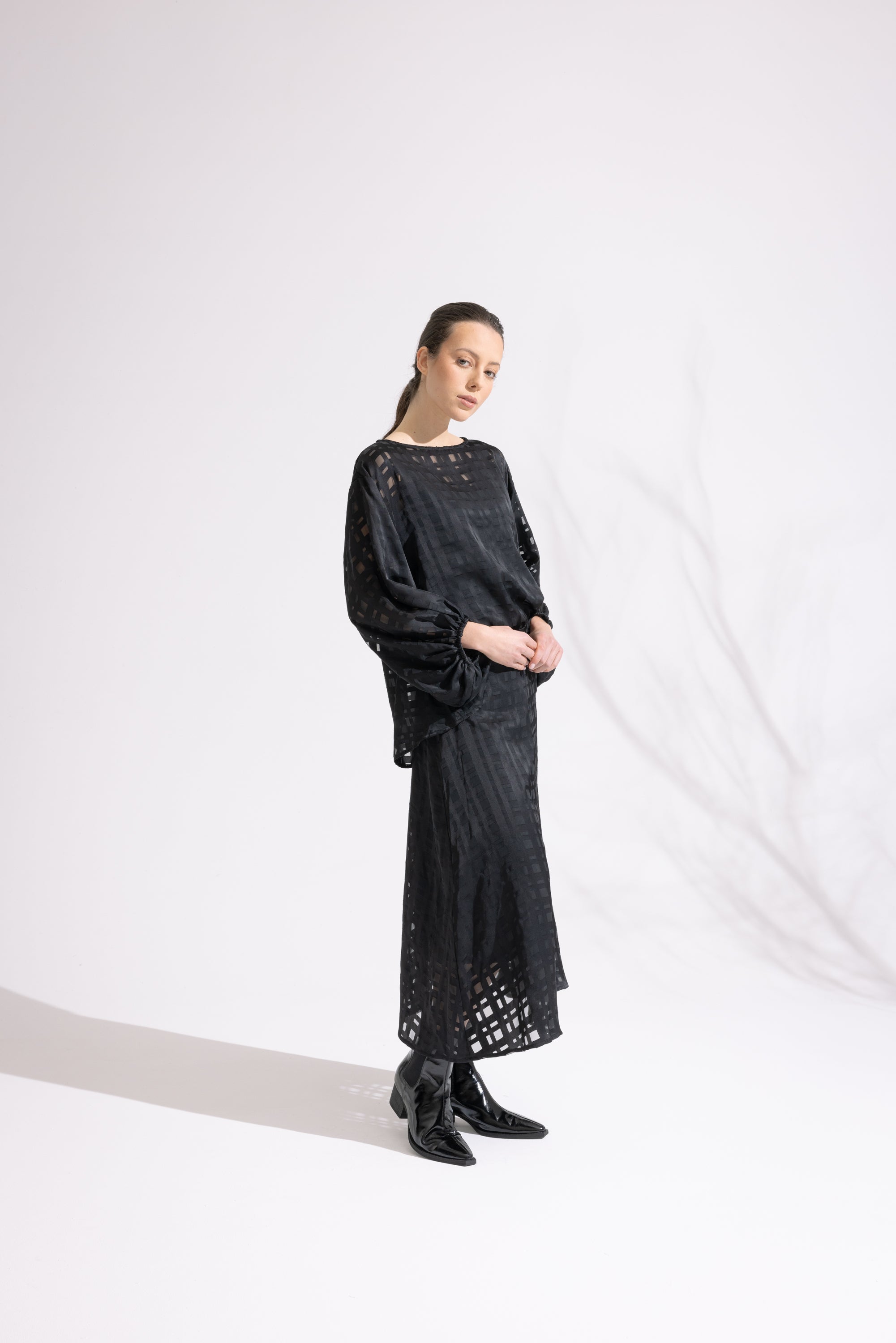 Person wearing a black outfit with lace details on a white background