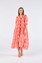 women wearing a coral dress with rectangles on it in shades of pink white and red on a plain background