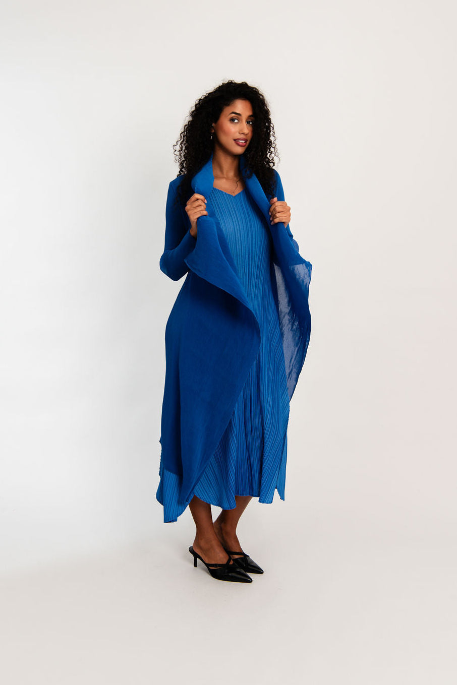 Woman wearing a blue dress with a matching jacket against a white background
