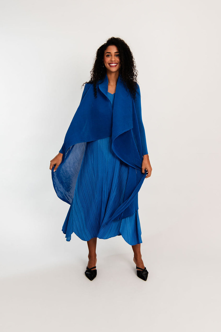 Woman wearing a blue dress with a draped top on a white background