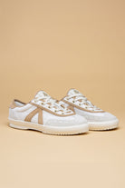 Pair of white sneakers with brown accents on a beige background