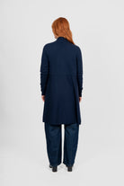 Person wearing a navy long cardigan and pants on a white background back angle