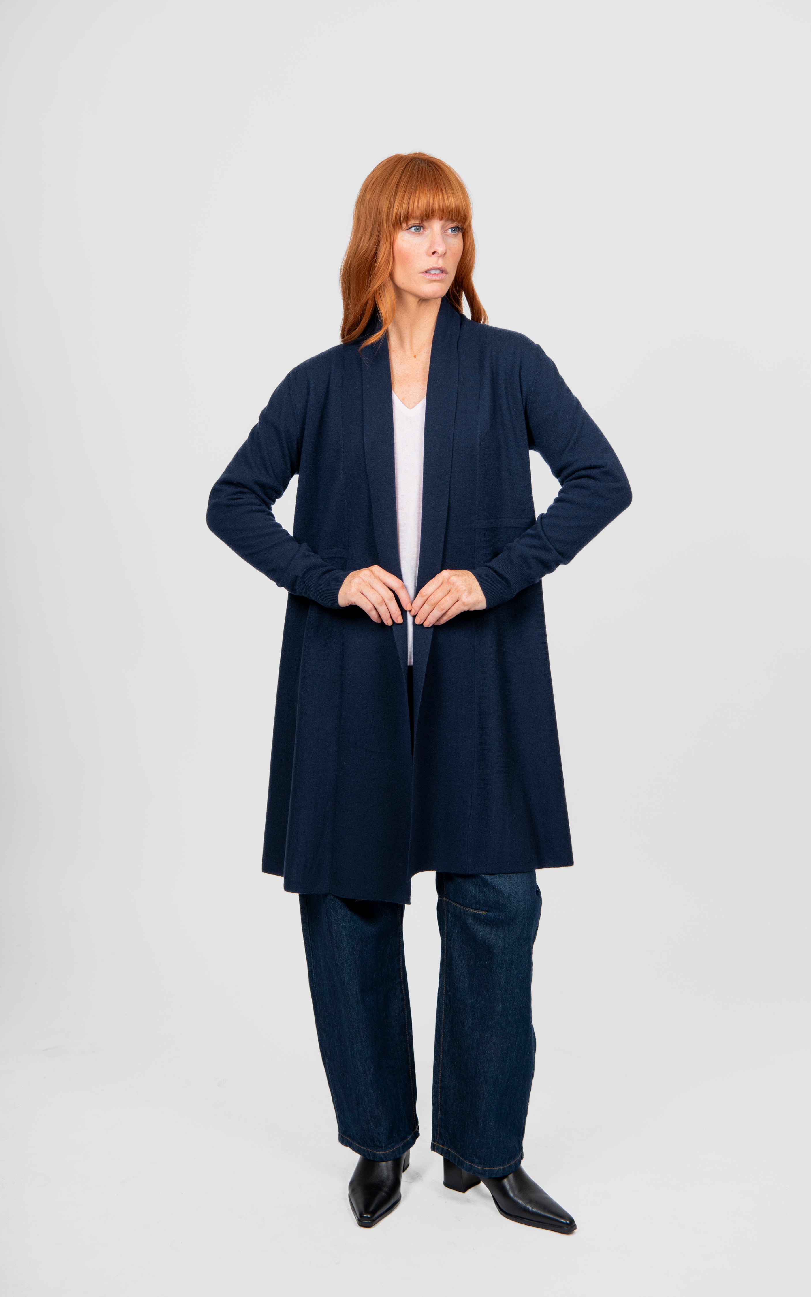 Woman wearing a navy blue cardigan and pants on a white background