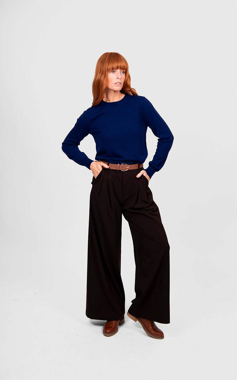Woman wearing a blue sweater and black wide-leg pants on a white background