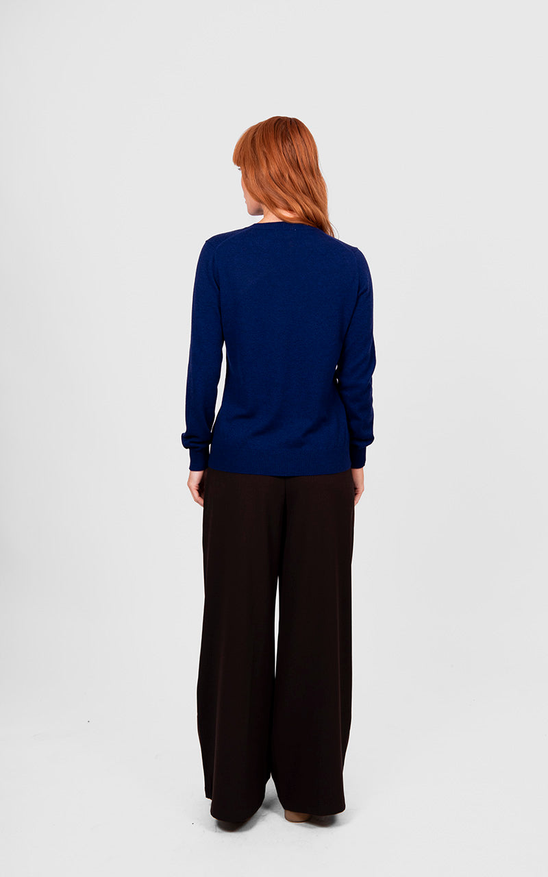 Person wearing a blue sweater and black pants on a white background