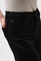 Black pants with a textured gray top on a white background close up