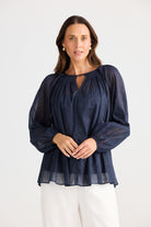Woman wearing a navy blue blouse with long sleeves on a white background