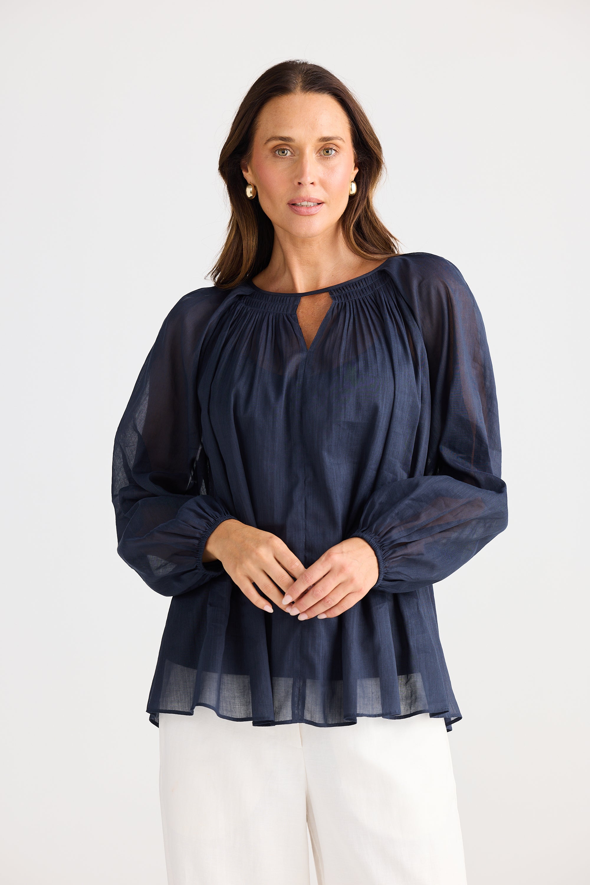 Woman wearing a navy blue blouse with long sleeves on a white background