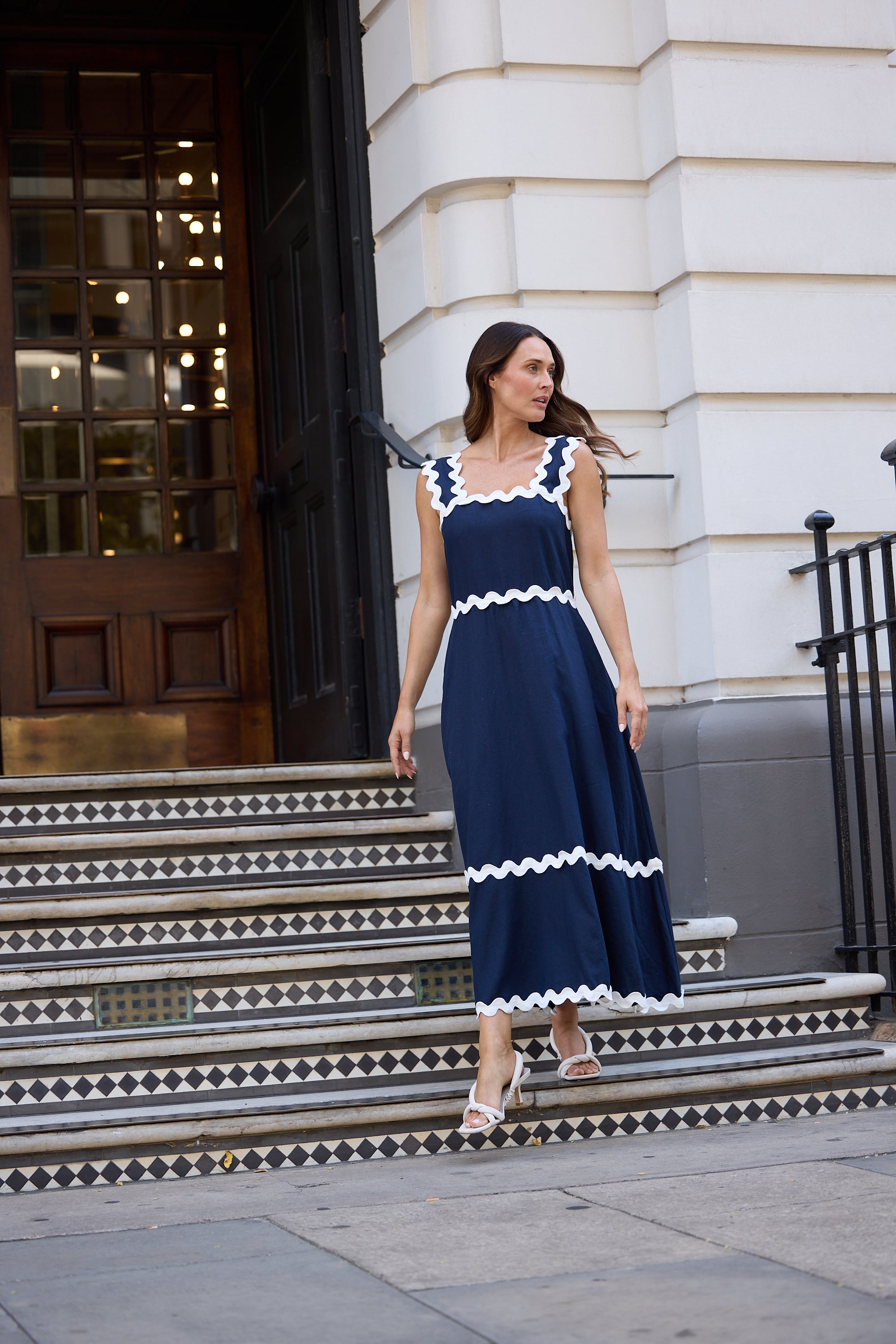 Woman in a navy dress with white trim standing on steps in an urban setting