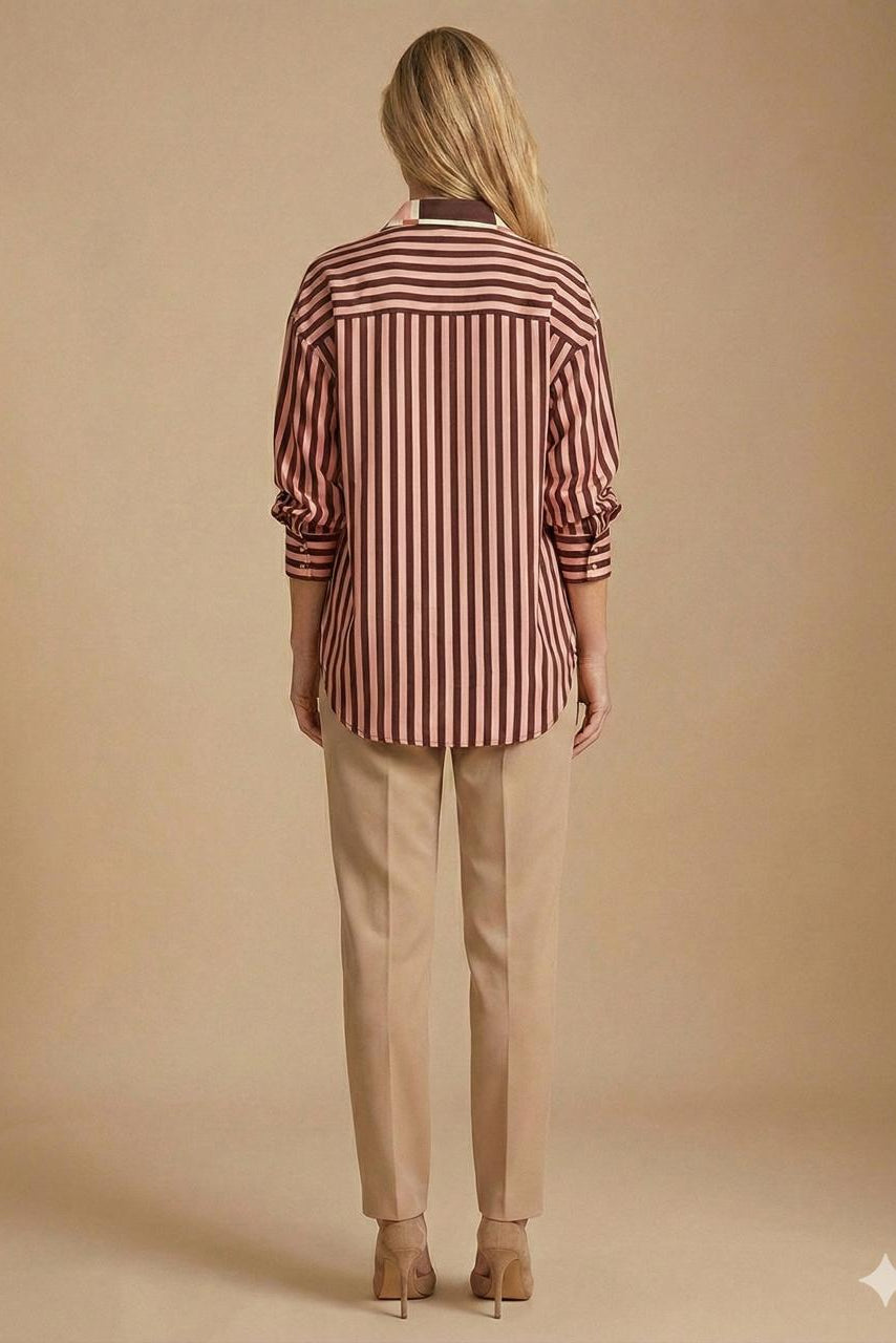 A woman viewed from behind wearing a long-sleeve button-up shirt with vertical burgundy and beige stripes, paired with beige trousers and beige heels, against a solid beige studio background.