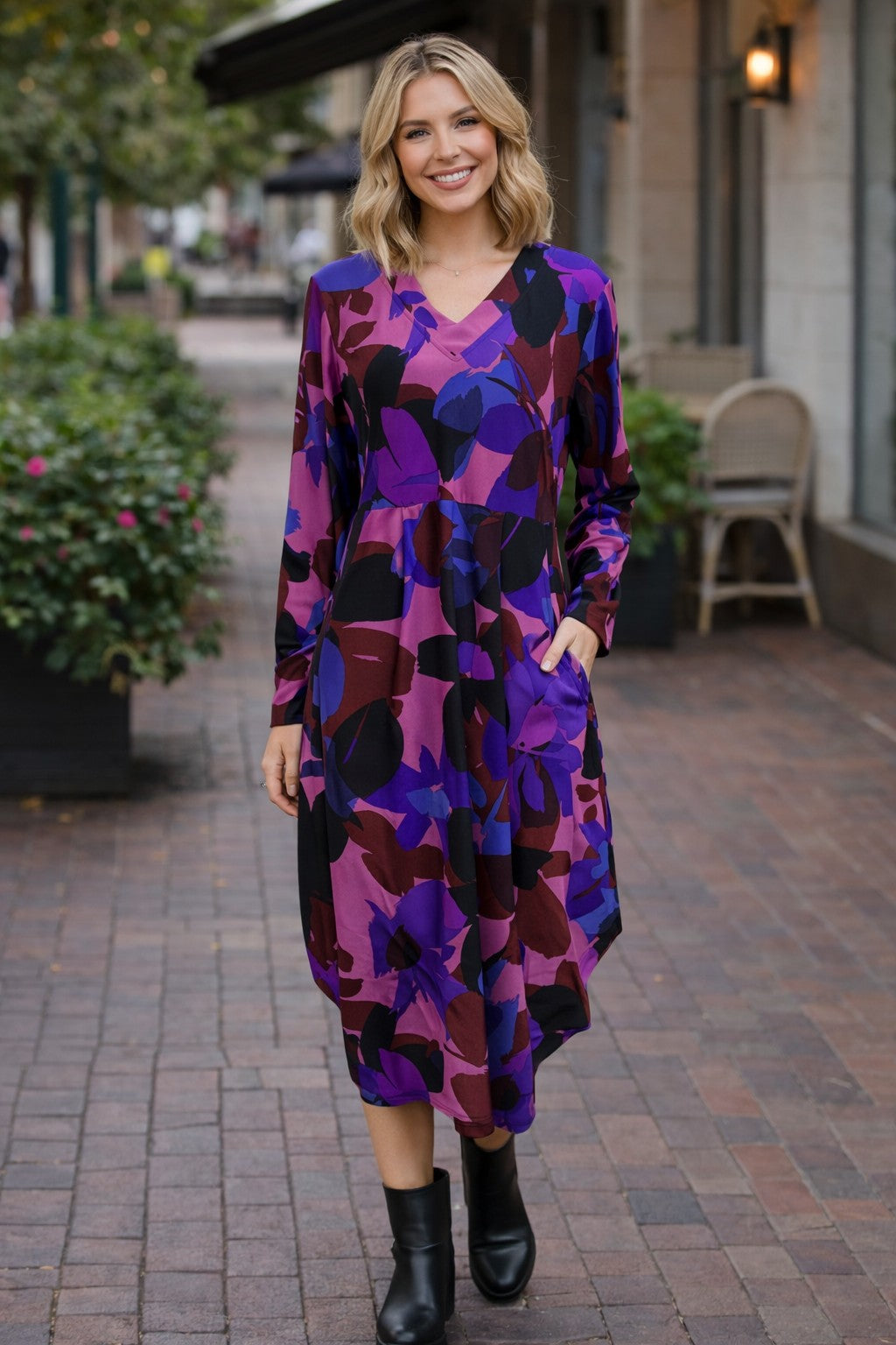 Woman wearing a multi purple floral dress standing on a sidewalk