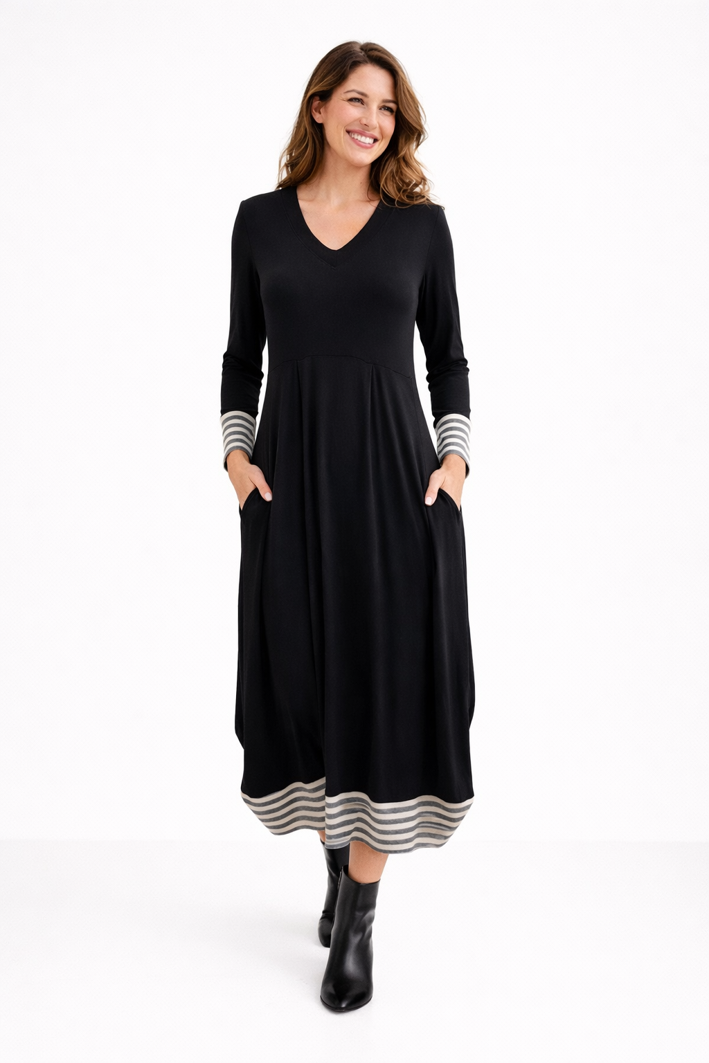 Woman wearing a black dress with striped cuffs and hem on a white background