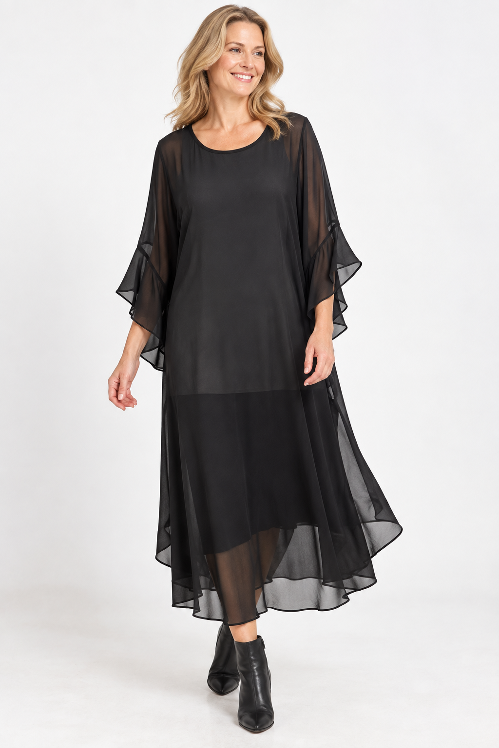 Woman wearing a black floaty chiffon dress against a white background.