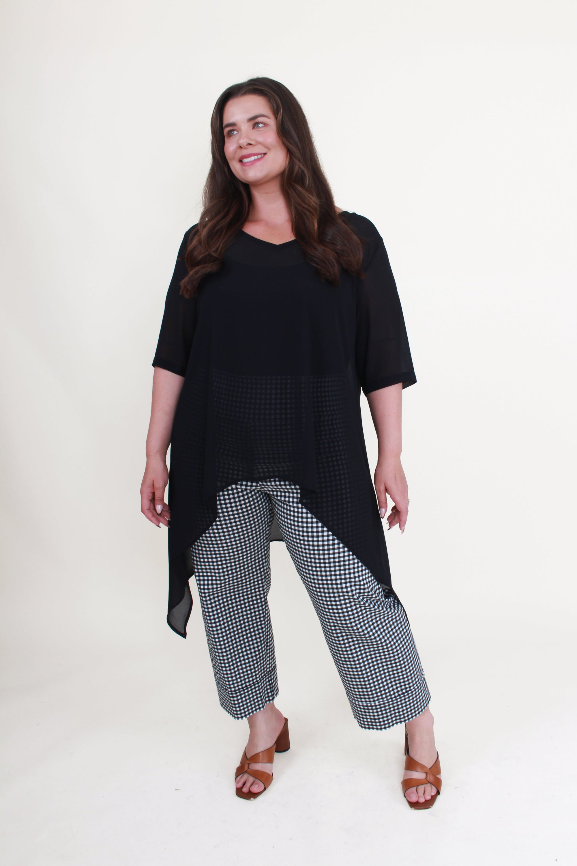 Woman wearing a black top and checkered pants on a white background