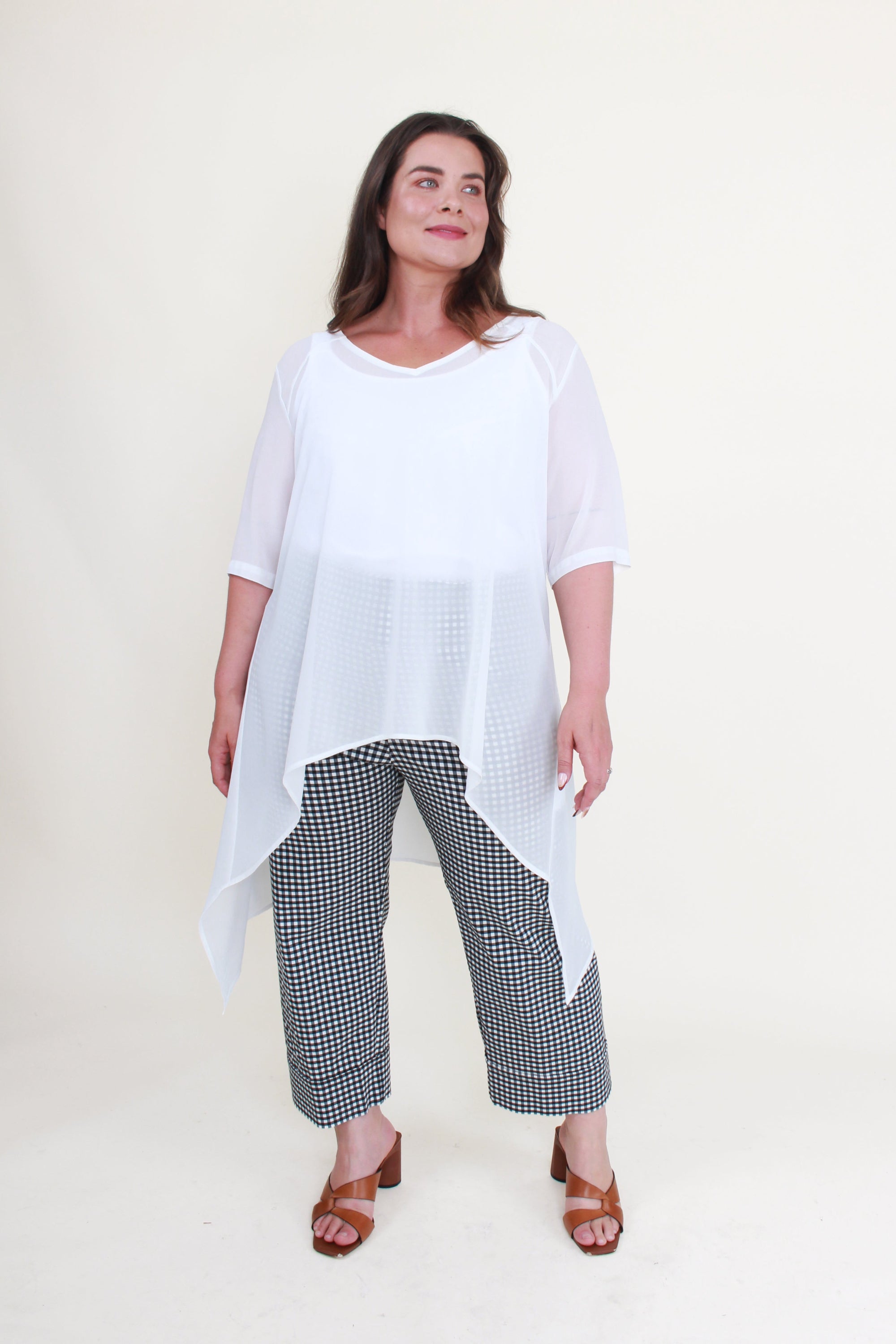 Woman wearing a white top and checkered pants on a plain background