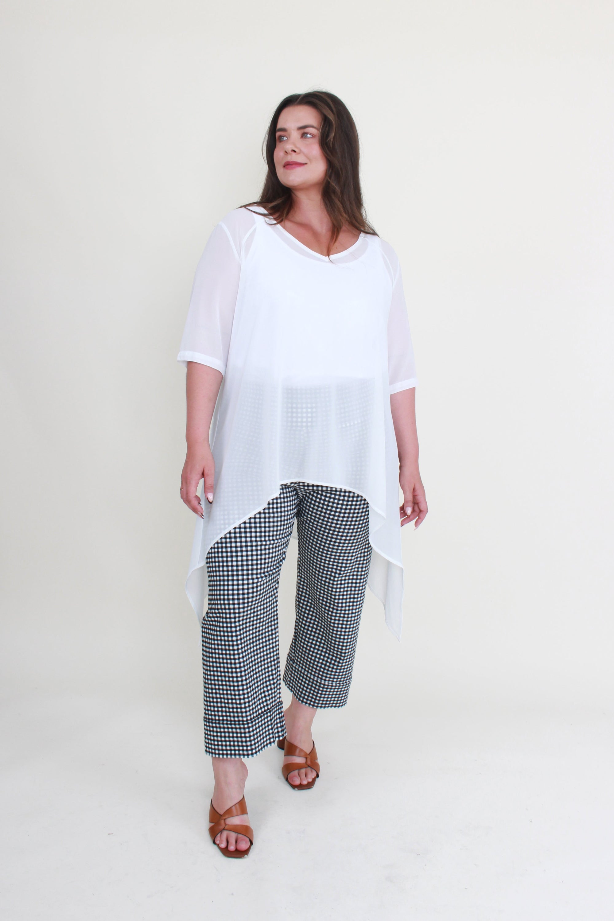 Woman wearing a white top and checkered pants on a white background