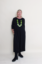 Woman wearing a black dress with a green necklace on a white background