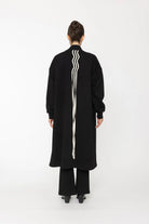Person wearing a black coat with white stripes on a white background