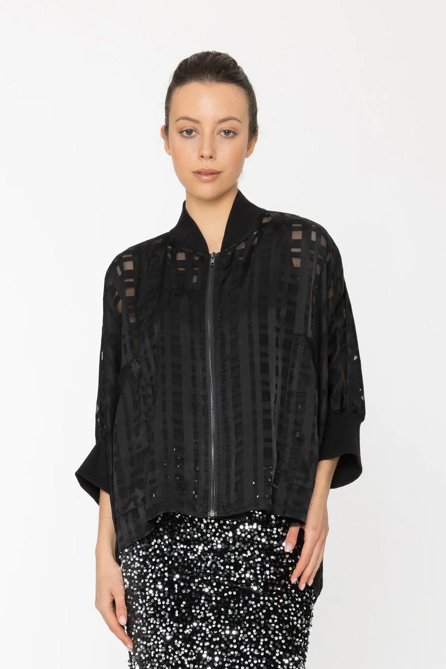 Woman wearing a black textured jacket with sheer sleeves on a white background
