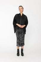 Woman wearing a black lace top and patterned skirt on a white background