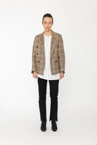 Person wearing a plaid blazer over a white shirt with black pants on a white background