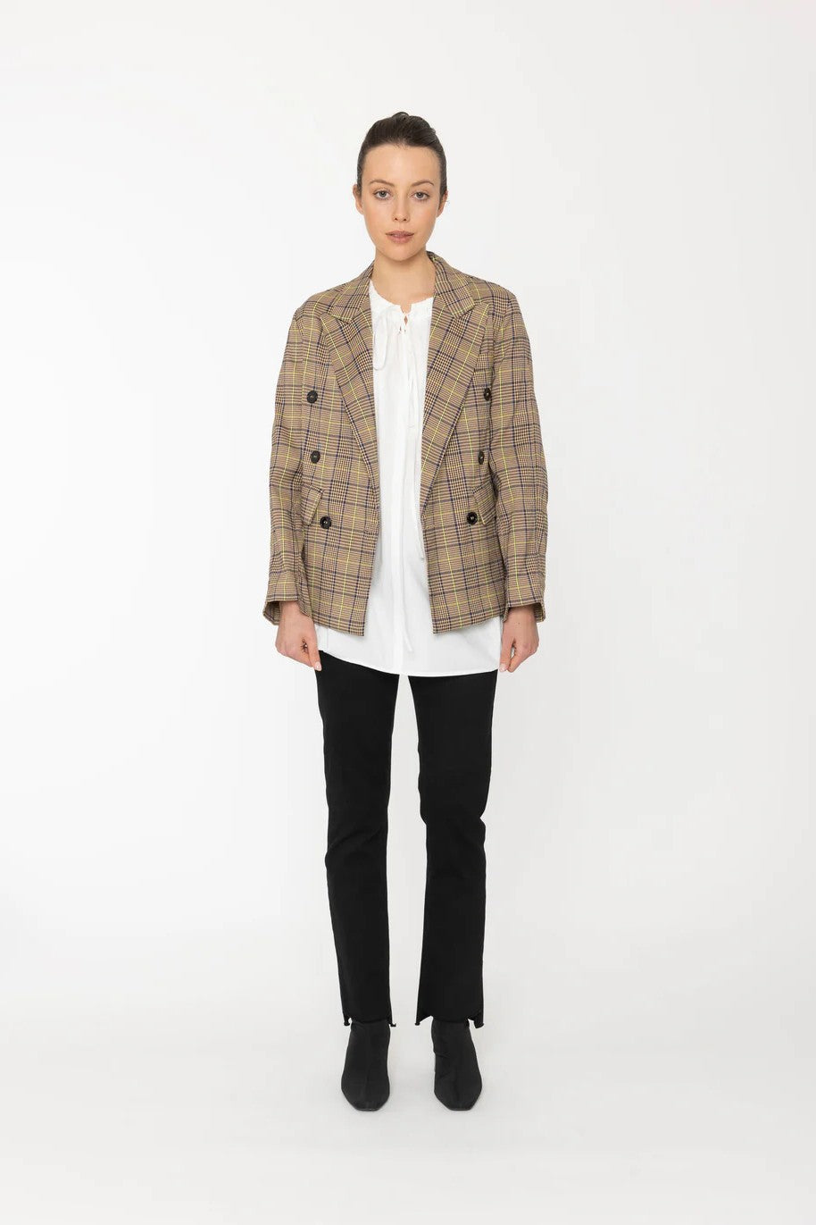 Person wearing a plaid blazer over a white shirt with black pants on a white background