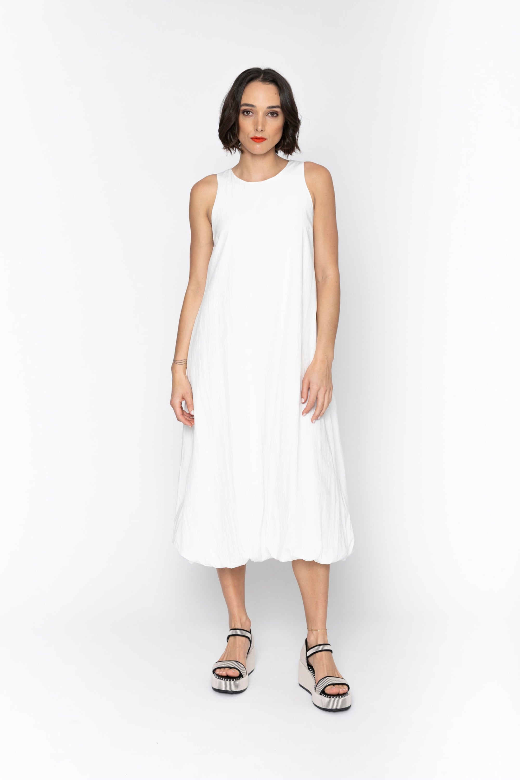 Woman wearing a white sleeveless dress on a white background