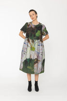 Woman wearing a colorful dress with nature-themed print on a white background