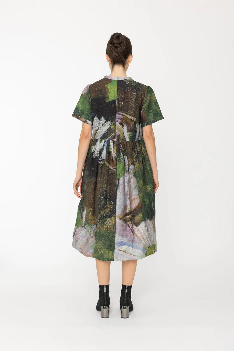 Woman wearing a green abstract patterned dress on a white background back angle