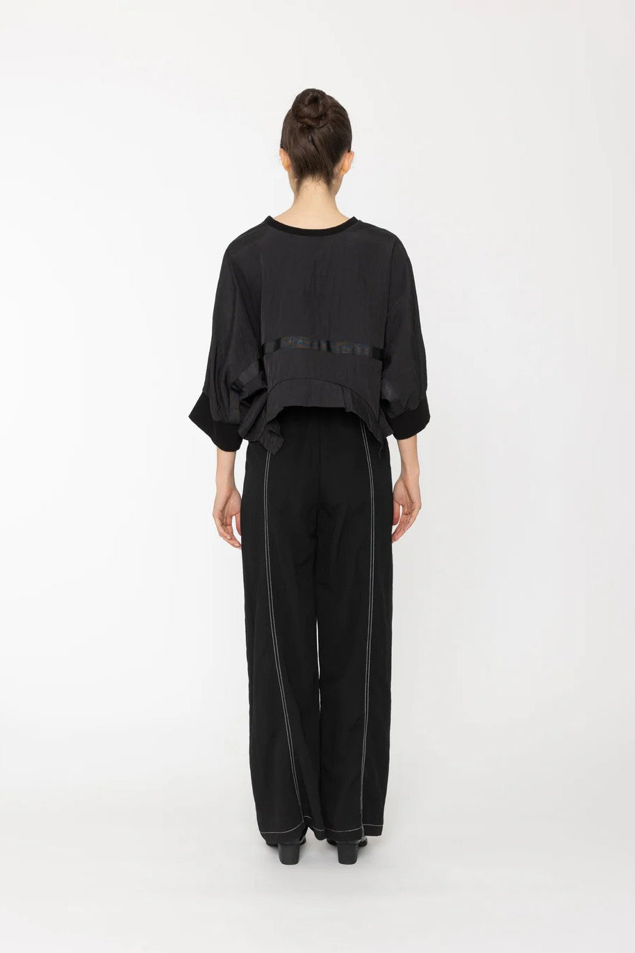 Person wearing a black outfit on a white background back angle