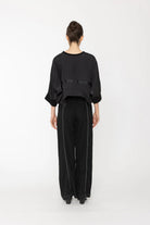Person wearing a black outfit on a white background back angle