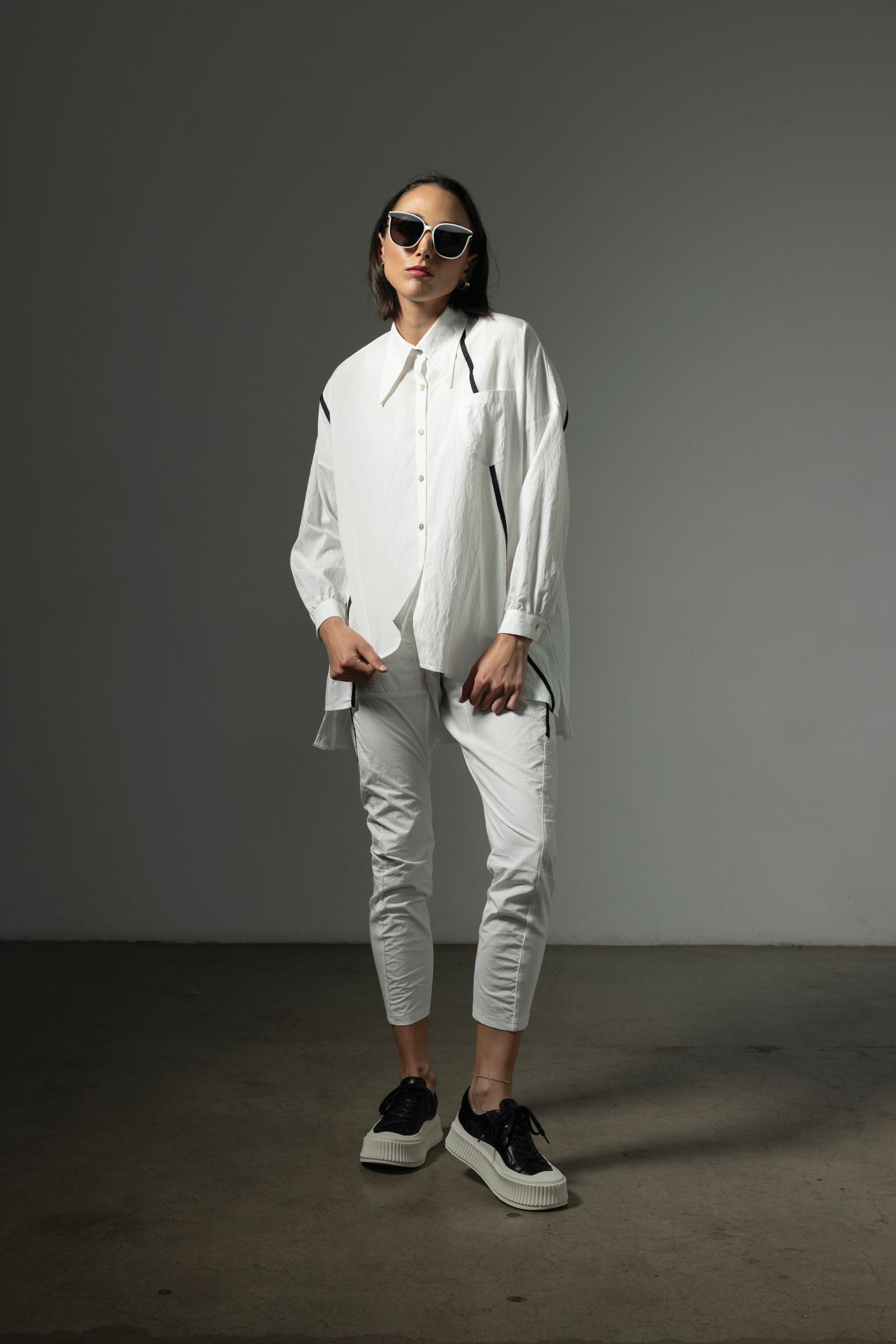 button through step hem shirt white with black details and white pant worn by model 